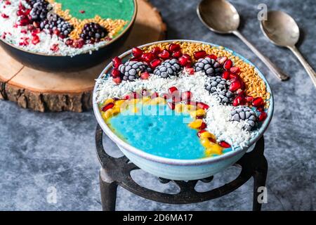 Blue and green spirulina smoothie bowls with fruit and linseed - healthy superfood breakfast idea. Stock Photo