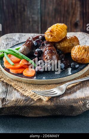 Venison sausages with vegetables, baked baby potatoes and blueberry gravy Stock Photo