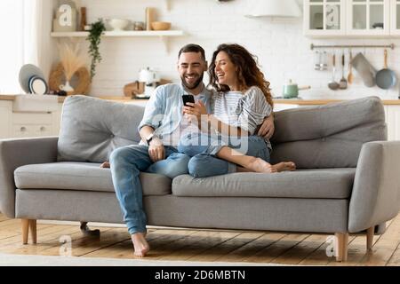 Happy young woman and man hugging, using smartphone together Stock Photo