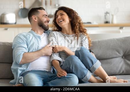 Happy married young couple hugging, sitting on couch together Stock Photo