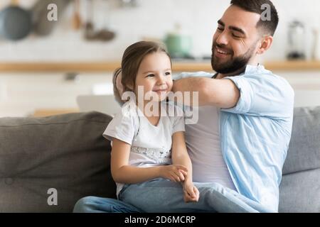 Caring smiling father brushing combing adorable preschool daughter hair Stock Photo