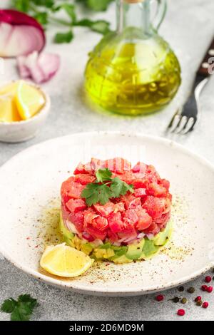 Tuna tartare tartar with avocado and purple onion. Served with cilantro (coriander), lemon and freshly ground pepper. Delicious appetizer (salad) of r Stock Photo