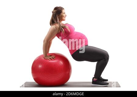 Profile shot of a pregnant woman exercising with a fitness ball isolated on white background Stock Photo