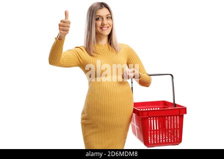 Smiling pregnant woman holding a shopping basket and showing thumbs up isolated on white background Stock Photo