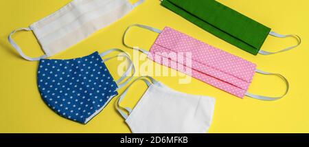 Five colored different medical masks on yellow isolated background. Hygienic antimicrobial, antiviral tissue masks. Protective equipment against coron Stock Photo