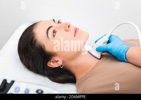 Woman patient receives thyroid diagnostics. Treatment of thyrotoxicosis, and hypothyroidism. Ultrasound diagnostics of the endocrine system and thyroi Stock Photo