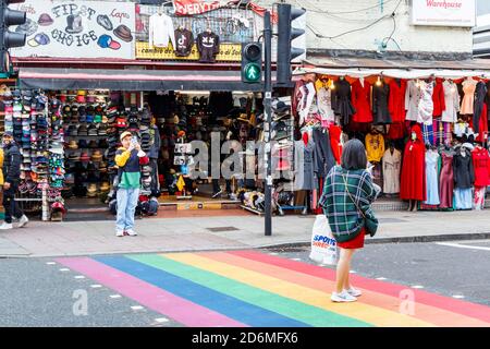 A woman pauses to be photographed on a rainbow pedestrian crossing in Camden Town, London, UK Stock Photo