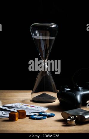 Games night hourglass background staying in with friends staying home poker chips dice & cards video games controller on wooden table. Stock Photo