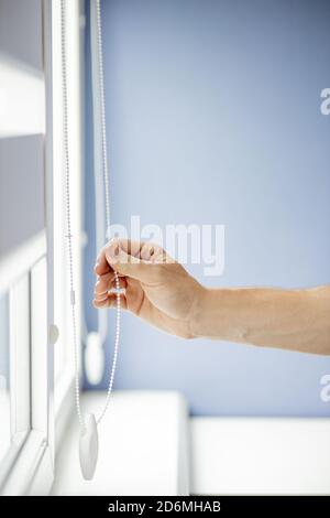 Man testing cassette roller blinds on windows. Stock Photo