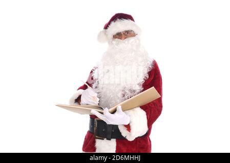 Senior man wearing a traditional Santa Claus costume writing with a quill pen in his Naughty and Nice Book. Isolated on white. Stock Photo