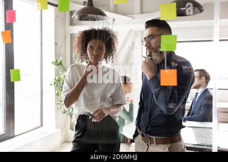 Thoughtful young concentrated multiracial employees looking at marketing chart. Stock Photo