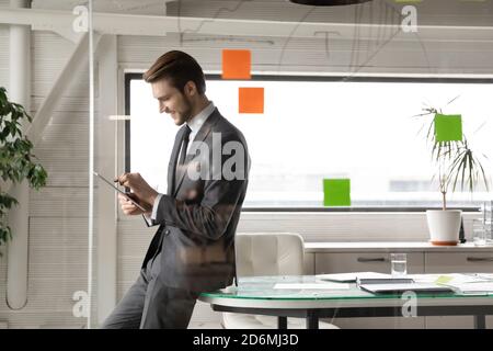 Smiling young businessman using digital computer tablet in office. Stock Photo