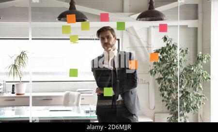 Thoughtful young businessman analyzing project sales data alone in office. Stock Photo