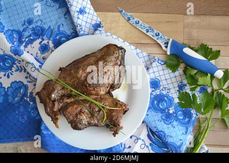 Roasted hare legs on rustic wooden surface with blue and white decoration Stock Photo