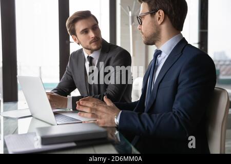 Focused confident two business partners discussing online project computer presentation. Stock Photo