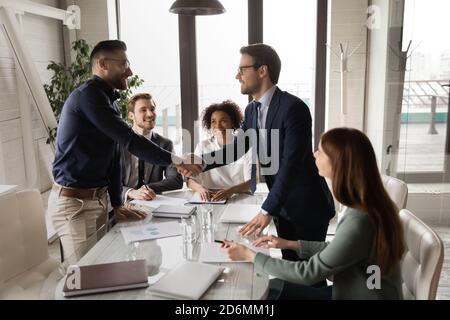 Two male confident partners shaking hands, establishing profitable cooperation. Stock Photo