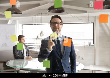 Smiling young executive manager holding sticky colored paper in hands. Stock Photo