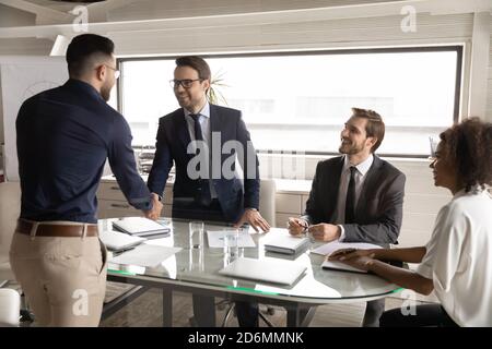 Happy 30s caucasian businessman shaking hands with arabian partner. Stock Photo