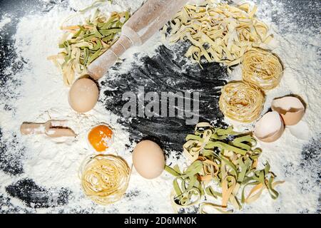 Pasta with ingredients - flour, eggs and different tools for cooking on black table. Free space for text . Top view. Stock Photo