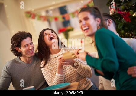 Group of friends celebrating Christmas by pulling crackers Stock Photo