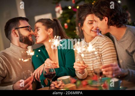 Group of friends holding sparklers celebrating Christmas at home Stock Photo