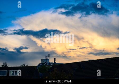 Mammatus clouds below the anvil of a thunderstorm are illuminated by the light of the setting sun. Stock Photo