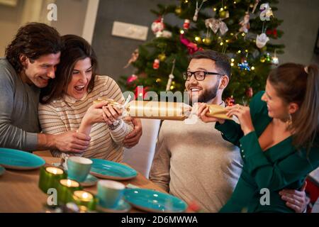 Group of friends celebrating Christmas by pulling crackers Stock Photo