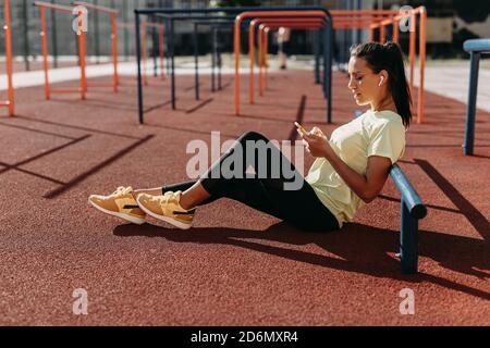 Pretty woman using smartphone while sitting at red court Stock Photo