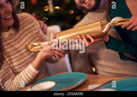 Group of friends celebrating Christmas by pulling crackers Stock Photo