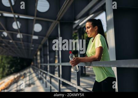 Sporty woman with bottle of water resting after training Stock Photo