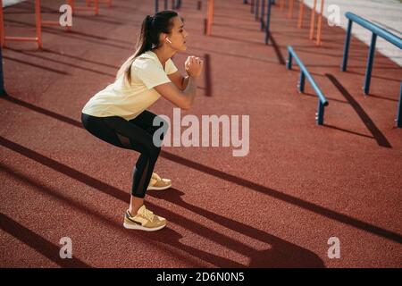 Side view of woman in activewear squatting on fresh air Stock Photo