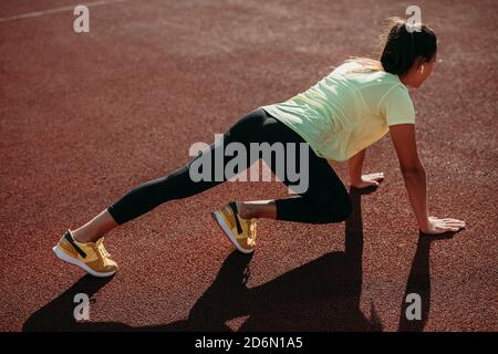 Back view of strong lady doing abs exercises at red court Stock Photo