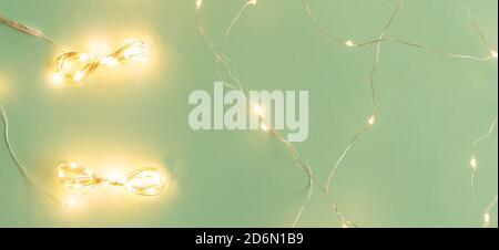 Christmas lights on light green background, flat lay with holiday garland Stock Photo