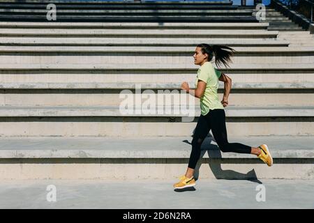 Focused female athlete jumping and running outdoors Stock Photo