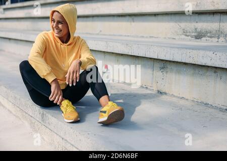 Cheerful woman in activewear resting on steps Stock Photo