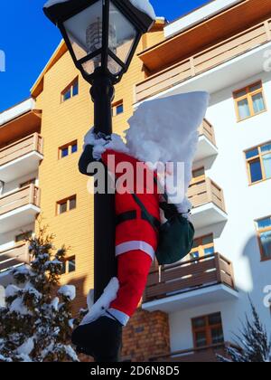 Toy santa claus hanging on a lamp post with a pile of snow on his head Stock Photo