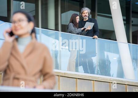 Young female with touchpad making presentation of financial data to mature man Stock Photo