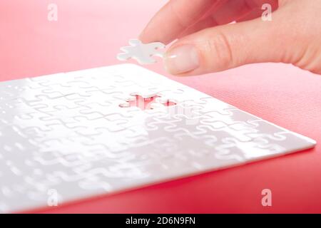 cropped image of businesswoman inserting last missing puzzle on red background, business concept Stock Photo