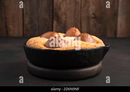 Pie in a baking dish on a wooden stand on a concrete brown background. Stock Photo