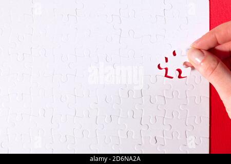 cropped image of businesswoman inserting last missing puzzle on red background, business concept Stock Photo