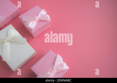 Boxes for small presents and gifts in pastel colors on a pink background with space for text. Advertising, poster. Stock Photo