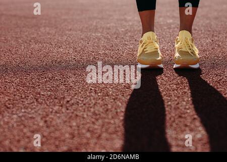 Close up of female runner in sneakers standing at red court Stock Photo