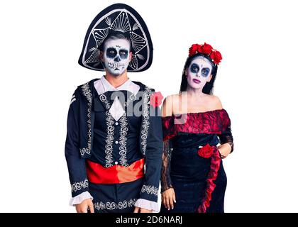 Young couple wearing mexican day of the dead costume over background looking sleepy and tired, exhausted for fatigue and hangover, lazy eyes in the mo Stock Photo