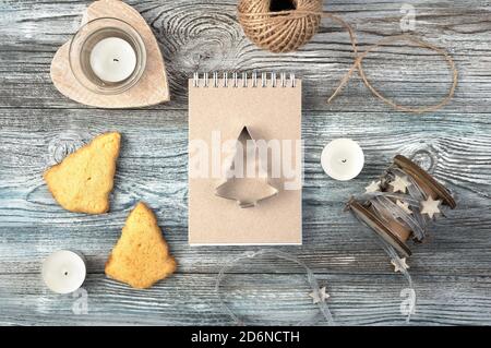 Christmas background with Notepad, iron shape of Christmas tree, cookies and candles on a wooden table. Stock Photo