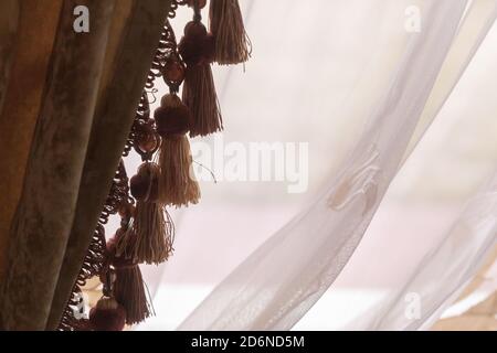 Decorative vintage luxury curtains fragment with fringe over white window. Close-up photo Stock Photo