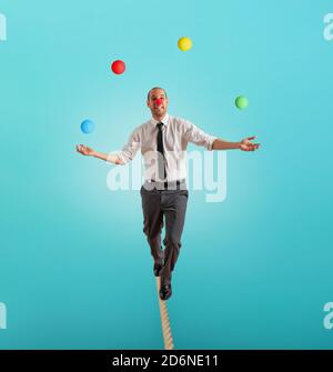 Worry man in balance walking on a rope overand acts like a juggler Stock Photo