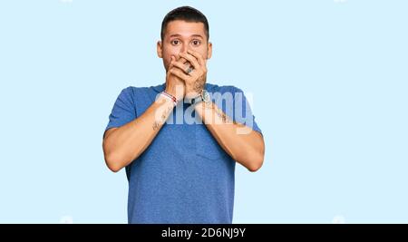 Handsome man with tattoos wearing casual clothes shocked covering mouth with hands for mistake. secret concept. Stock Photo