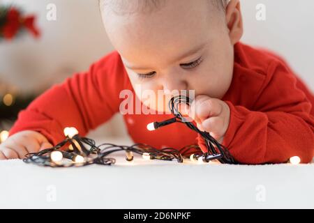 merry christmas and happy new year, infants, childhood, holidays concept - close-up 6 month old newborn baby in red clothes on his tummy crawls with Stock Photo
