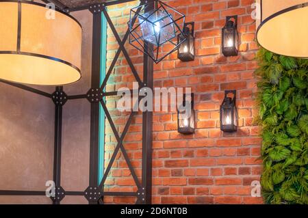 A fragment of the interior of a loft-style room with vintage lamps, a metal structure and a brick wall. Horizontal orientation, selective focus. Stock Photo