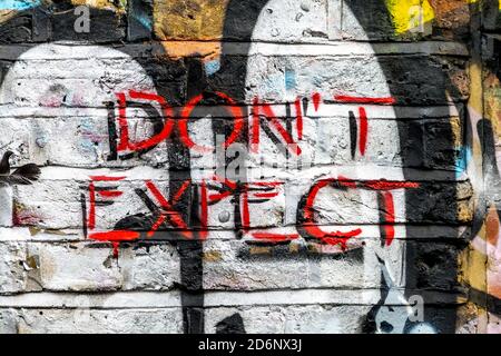 'Don't Expect' painted on a wall in Brick Lane, East London, UK Stock Photo
